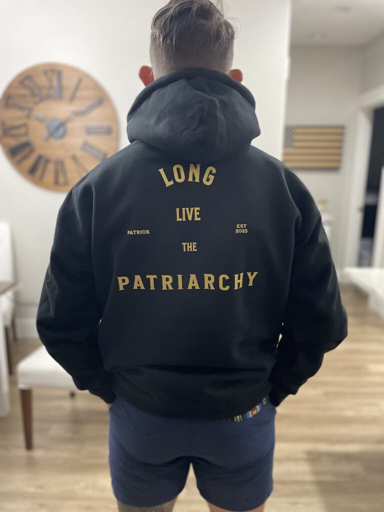 Man wearing black “Long Live the Patriarchy” hoodie with Patrios logo on front and bold statement on back, symbolizing masculine strength and tradition.