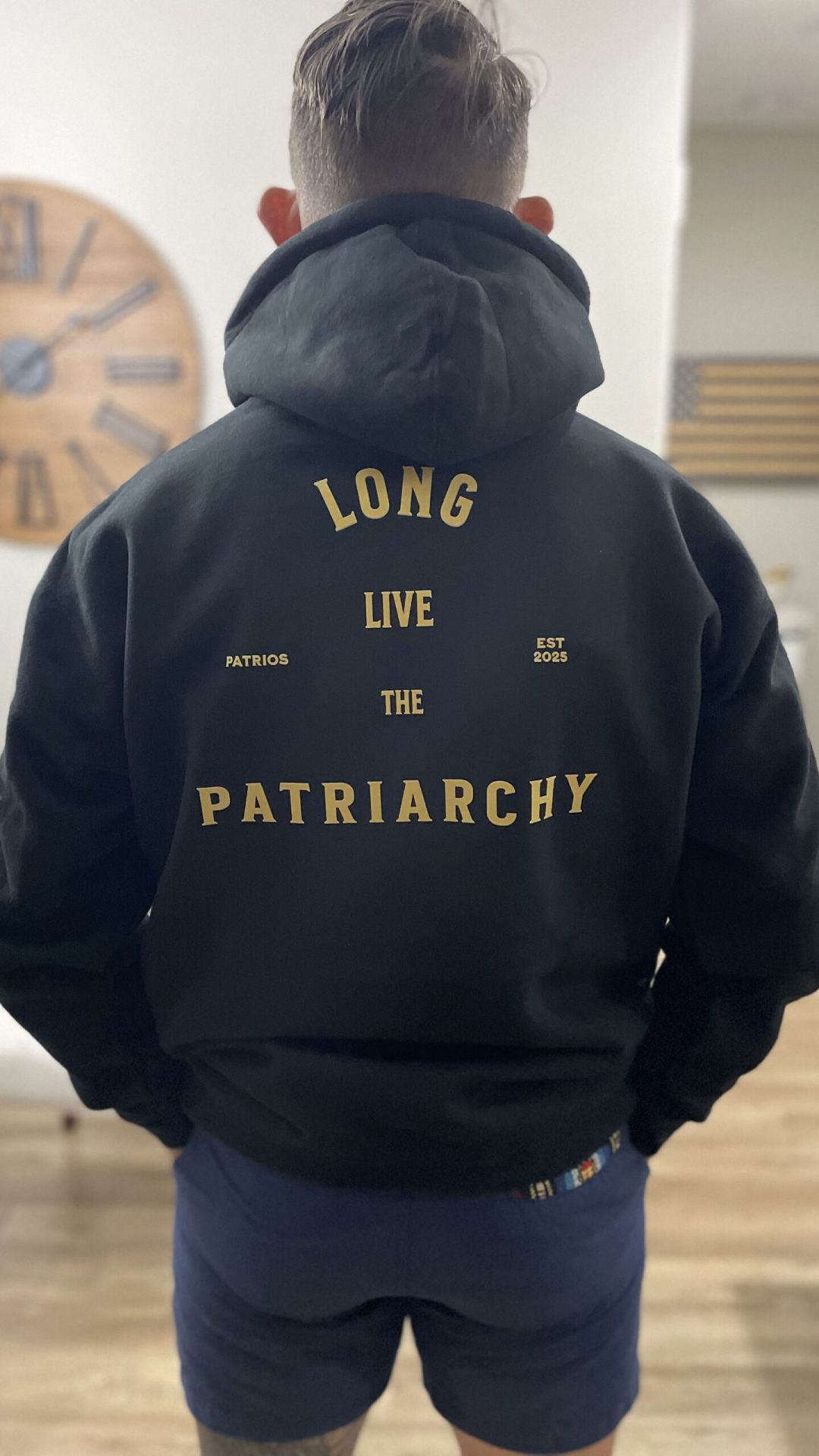 Man wearing black “Long Live the Patriarchy” hoodie with Patrios logo on front and bold statement on back, symbolizing masculine strength and tradition.